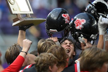 Mayer Lutheran tight end Teigan Martin (90), bottom right, celebrates with his team trophy after the Class 1A state championship football game between