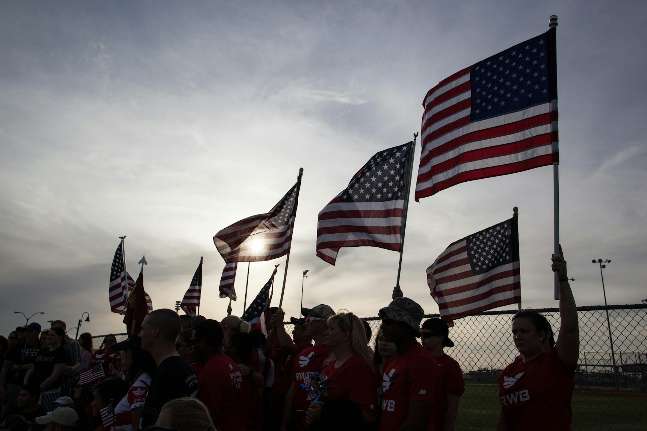 With American flags raised, active members of the military, veterans and civilians pose for a picture at Lions Club Park following a tribute walk in honor of the victims and families affected by the Fort Hood shooting, on Friday, April 4, 2014, in Killeen, Texas. On April 2, three people were killed and 16 were wounded when a gunman opened fire before taking his own life at the Fort Hood military base. (AP Photo/Tamir Kalifa)