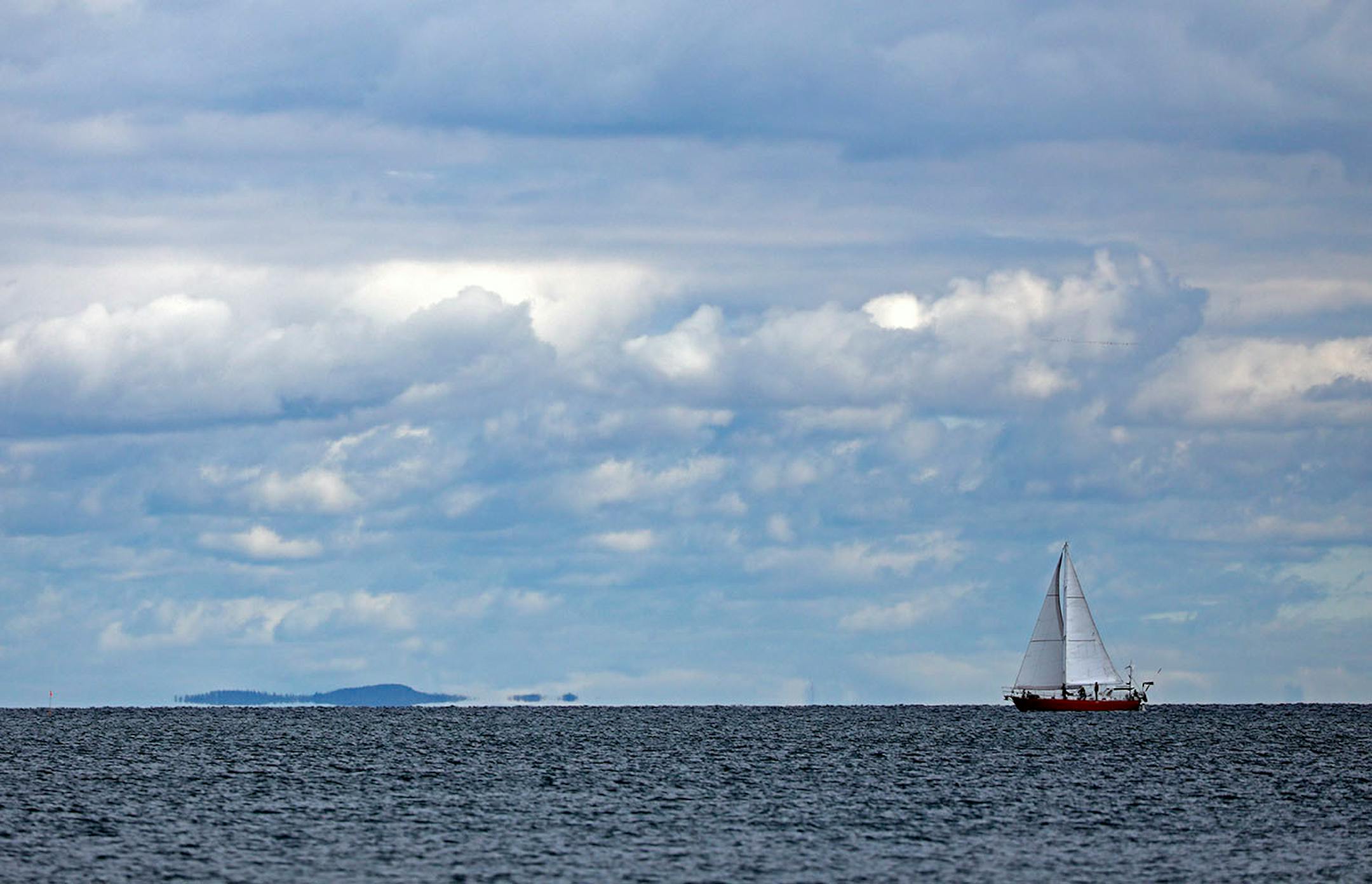 Mark and Katya Gordon sail Amicus out of Knife River, shown here with the Apostle Islands on the horizon.