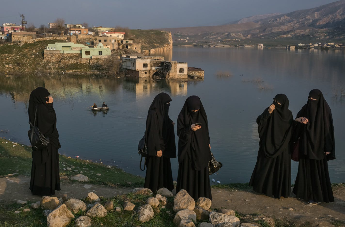 Visitors walk along the bank of the Tigris River as its rising waters flood the old town of Hasankeyf, Turkey, Feb. 24, 2020. In his push for economic development, Turkey's president has flooded the archaeological gem of Hasankeyf and displaced thousands of families. (Mauricio Lima/The New York Times)