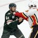 Minnesota Wild defenseman Matt Dumba (24)and Calgary Flames left wing Matthew Tkachuk (19) fight during the first period of an NHL hockey game Saturda