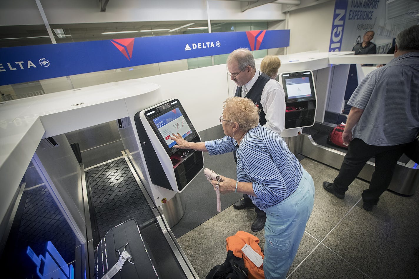 Delta Airlines ticket agent Chris Morris helped guide travelers through their new self-service bag drop machine at Minneapolis-St. Paul International Airport (MSP), Monday, June 19. Monday's check-in was a trial phase.