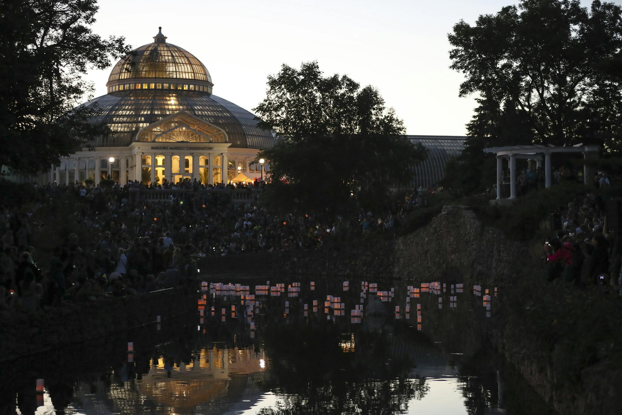 Lanterns floated in the Frog Pond near the Marjorie McNeely Conservatory in Como Park at dusk Sunday night. ] JEFF WHEELER ï jeff.wheeler@startribune.com The Como Park Conservatory's 18th annual Japanese Lantern Lighting Festival took place Sunday evening, August 21, 2016. Thousands gathered around the Frog Pond beside the Marjorie McNeely Conservatory in Como Park to watch as lanterns were floated on the water at dusk.