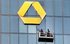 FILE - In this Sept. 23, 2016 photo window cleaners work at the logo of the Commerzbank building in Frankfurt. Shares in Deutsche Bank and Commerzbank