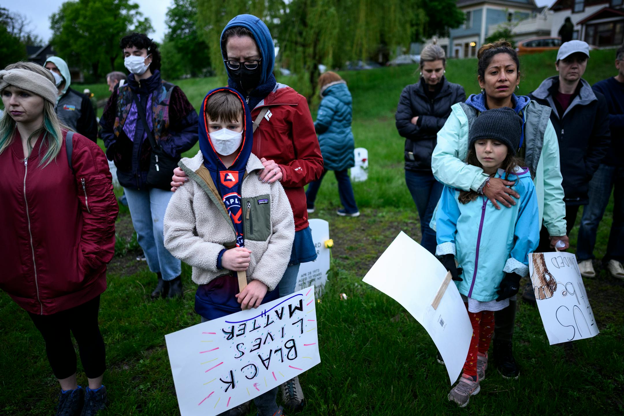 Community members bow their heads in a moment of silence during a vigil at the "Say Their Names" cemetery.