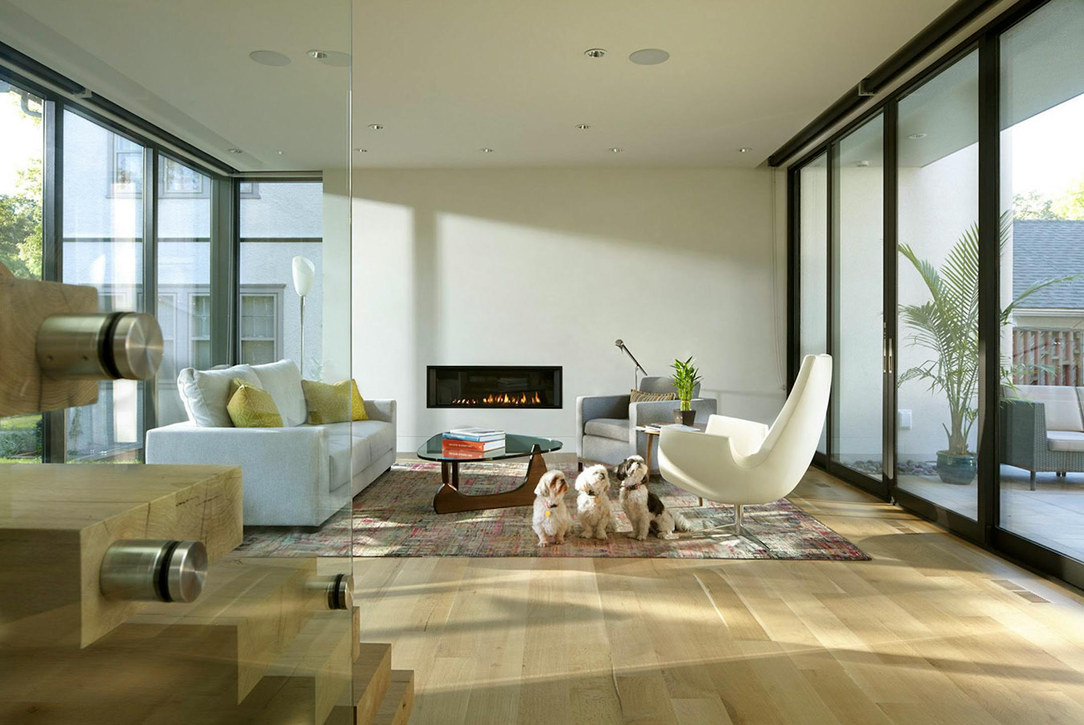 The living room has views of the street and backyard through walls of glass. A Venetian plaster wall surrounds the gas ribbon fireplace.