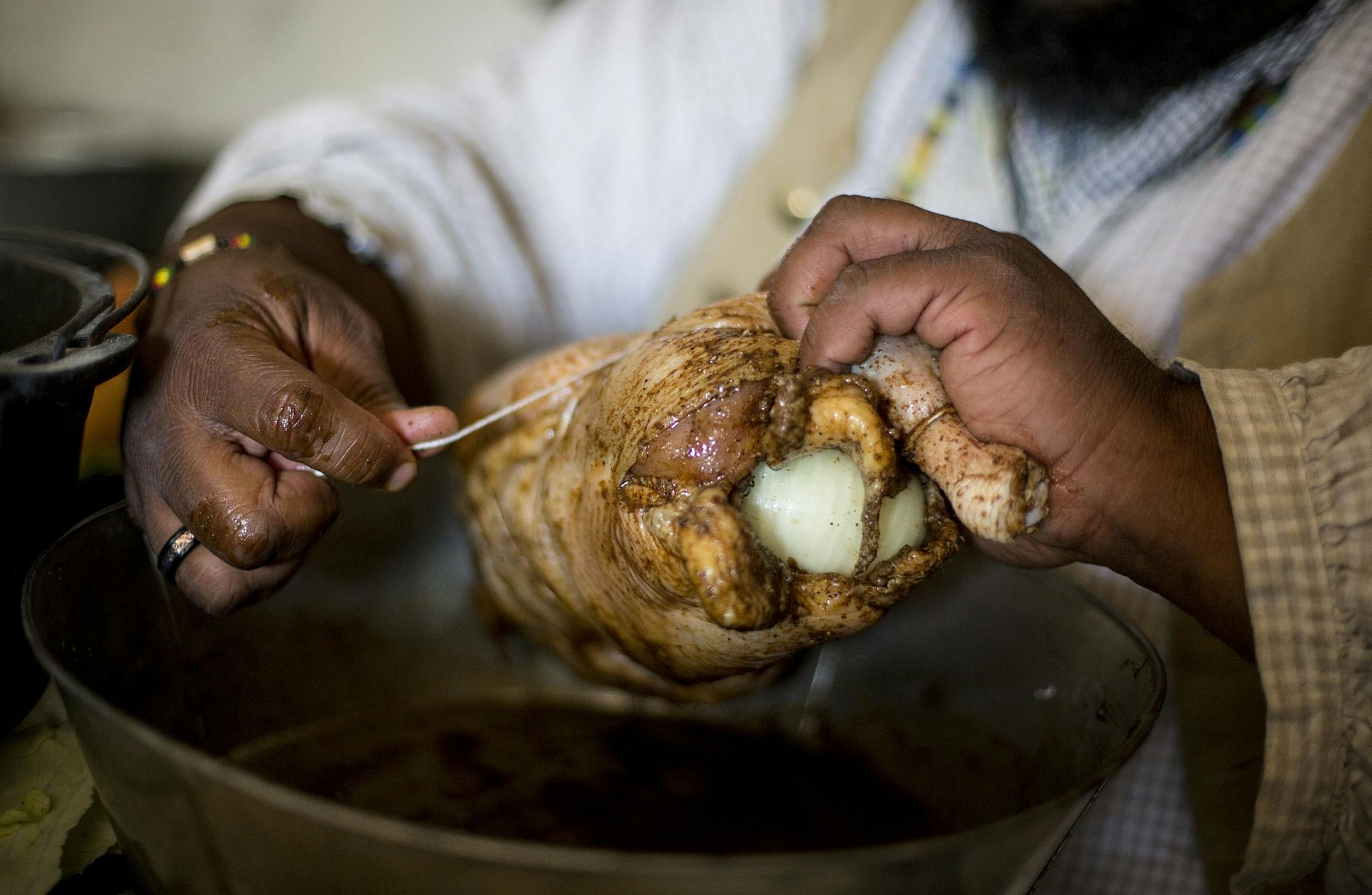 Michael Twitty binds the chicken together with twine before covering it in cabbage leaves to cook.