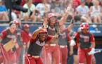 Oklahoma's Nicole Mendes (11) and Kelsey Arnold (3) celebrates a score in the fifth inning during the Women's College World Series softball game betwe