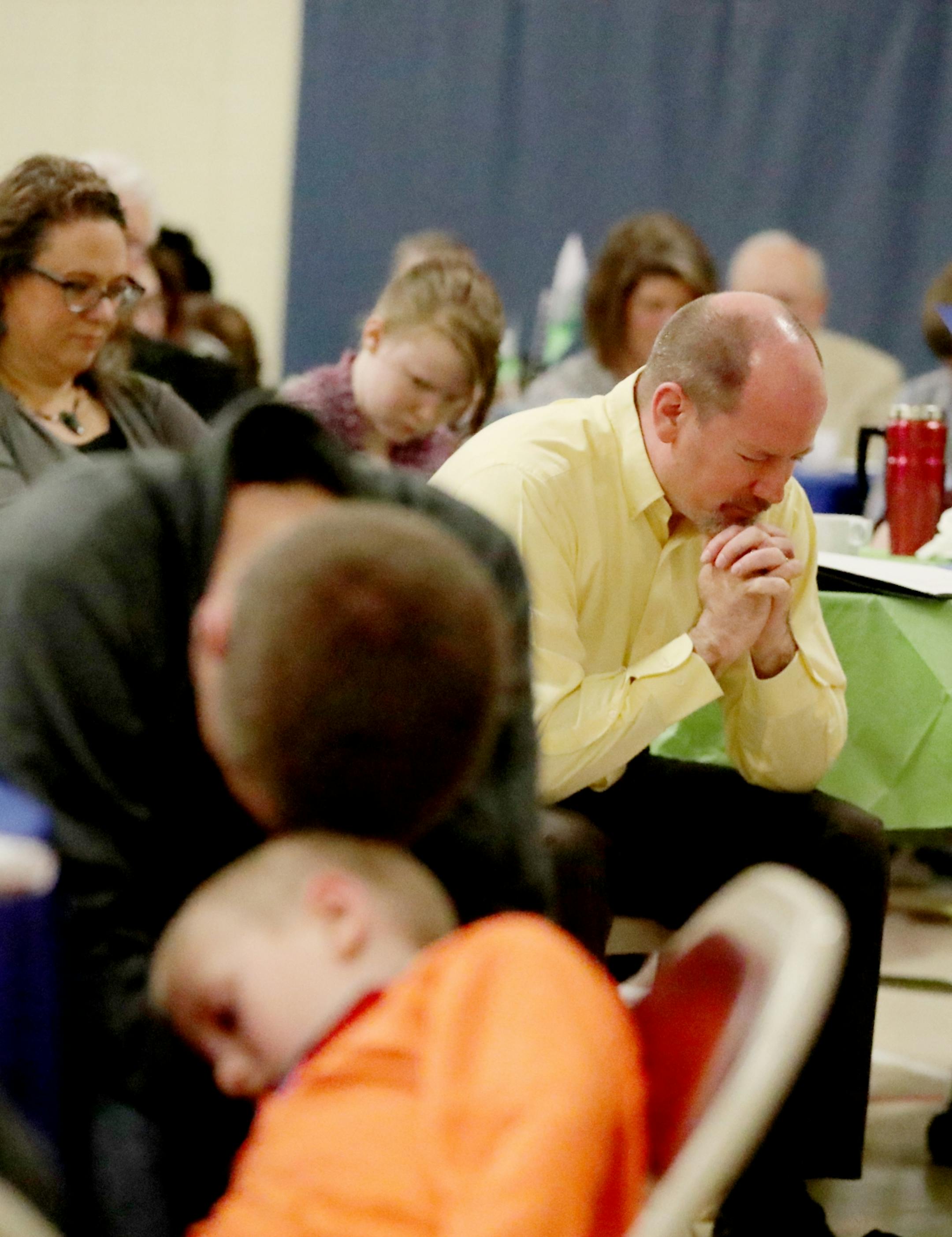 In an official ceremony entitled: Honoring the Past, Preparing for the Future: Trinity Baptist Church becomes Lifepoint Church Saturday, April 1, 2017, in St. Paul, MN. Here, Rev. Peter Vogt, in yellow, bowed his head in prayer.