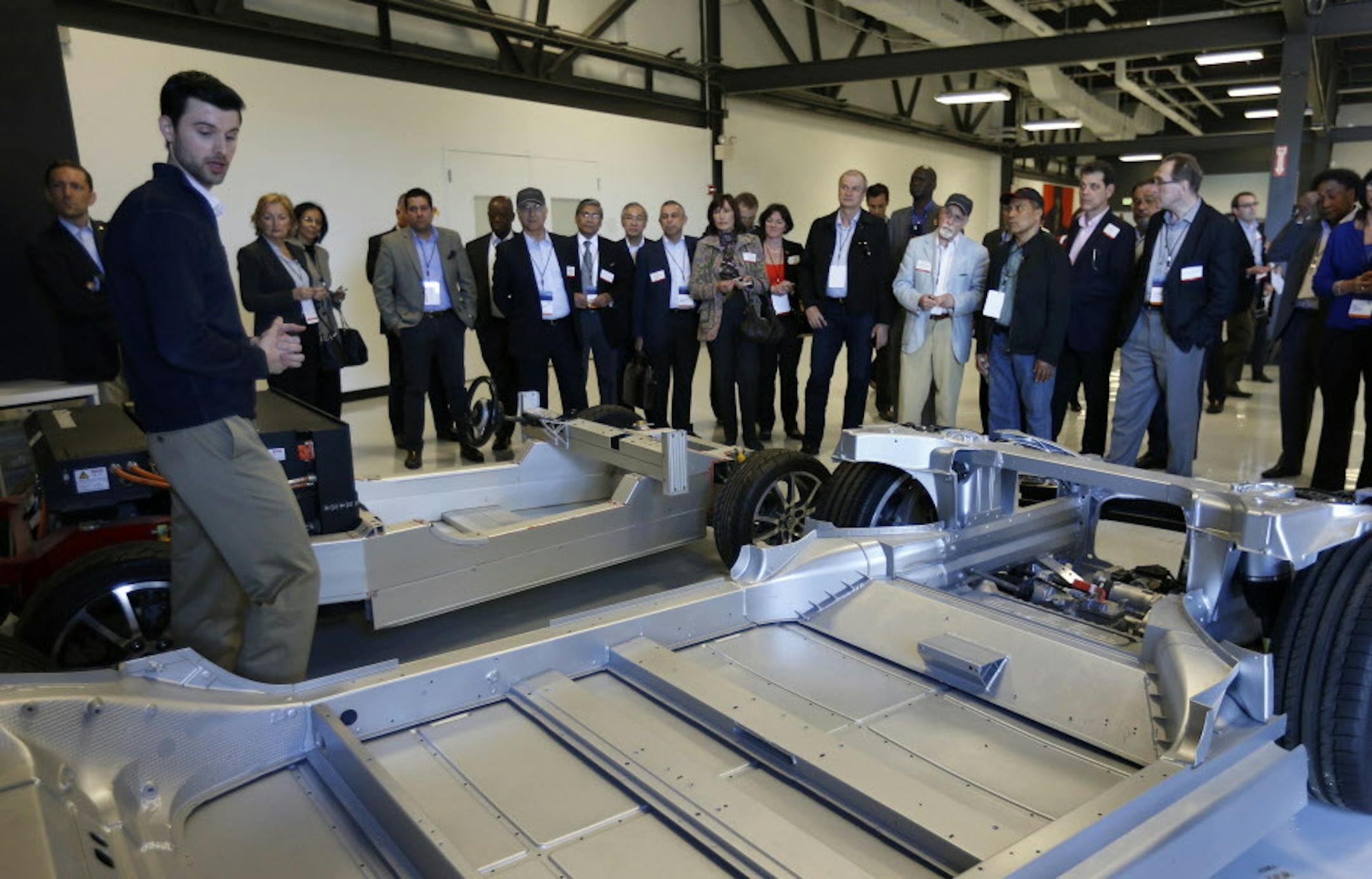 Tesla's Ken Morgan, far left, director of business development and government affairs, shows off the Tesla Model S chassis, foreground, and the Tesla Roadster chassis, background, to 35 ambassadors from around the world to the United States at Tesla in Palo Alto, Calif., on March 31, 2015. (Nhat V. Meyer/Bay Area News Group/TNS) ORG XMIT: 1166086