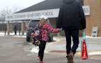 A parent walks his child to Orono Schumann Elementary School as a police officer stands nearby as students arrive for the day Thursday, Feb. 22, 2018,