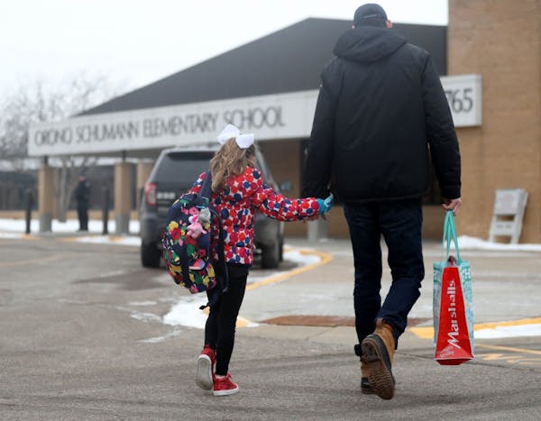 A parent walks his child to Orono Schumann Elementary School as a police officer stands nearby as students arrive for the day Thursday, Feb. 22, 2018,