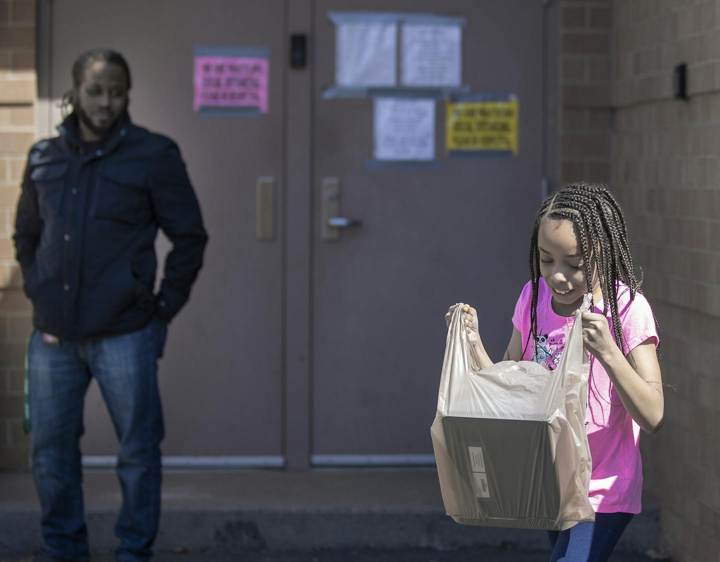 Harambee Elementary Principal Delon Smith looked on as student Nyaire Kirkwood, 9, checked out her Chromebook.