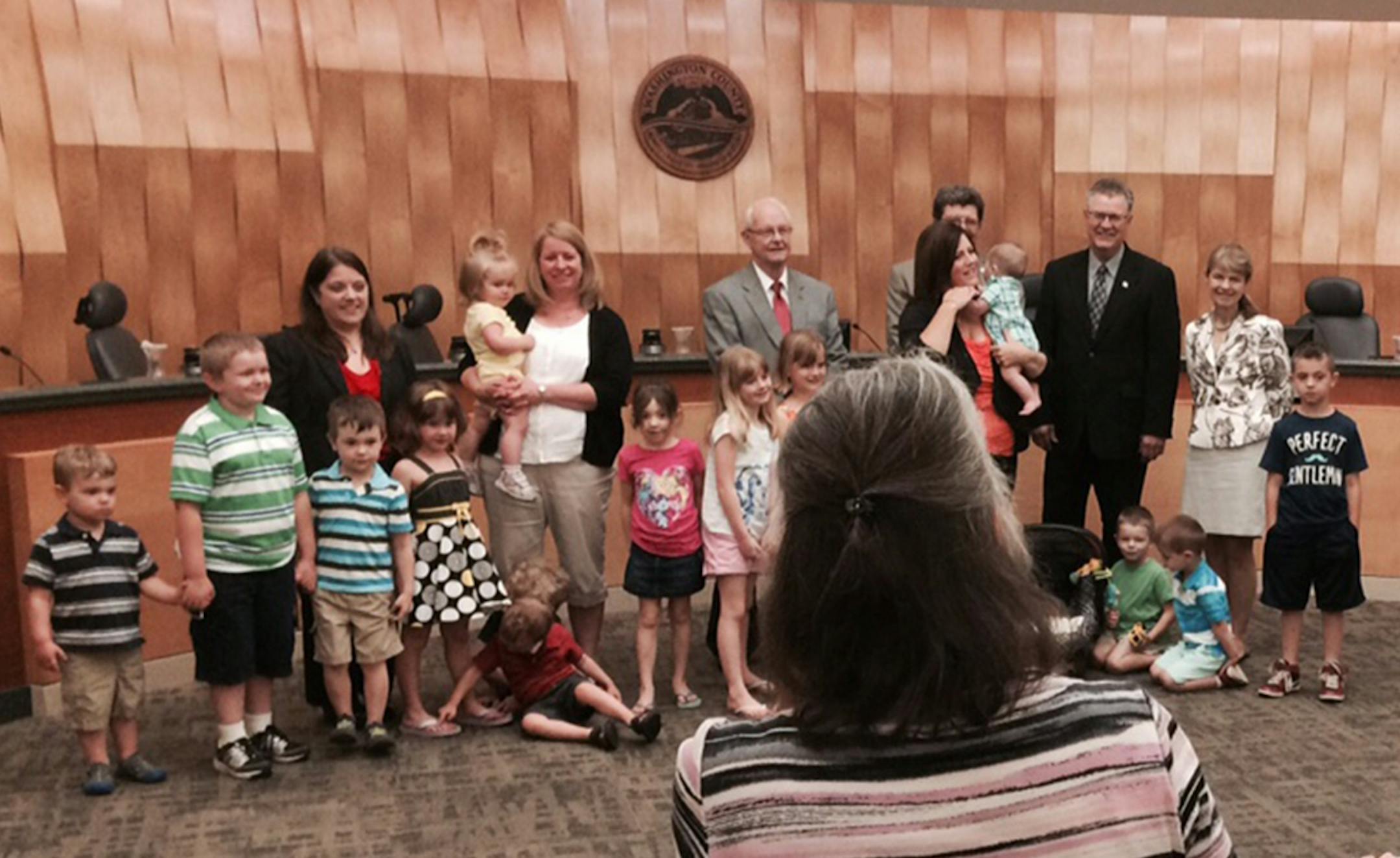 Day care providers Nancy Smith of Oakdale and Sarah Stadler of Cottage Grove were recognized last week as Washington County's "Family Care Providers of the Year." Smith is shown toward the right (dark hair, red top, holding a child) and Stadler to the left (light hair, white top, holding a child.) They're with commissioners (from left) Karla Bigham, Ted Bearth, Gary Kriesel, Lisa Weik and Fran Miron.