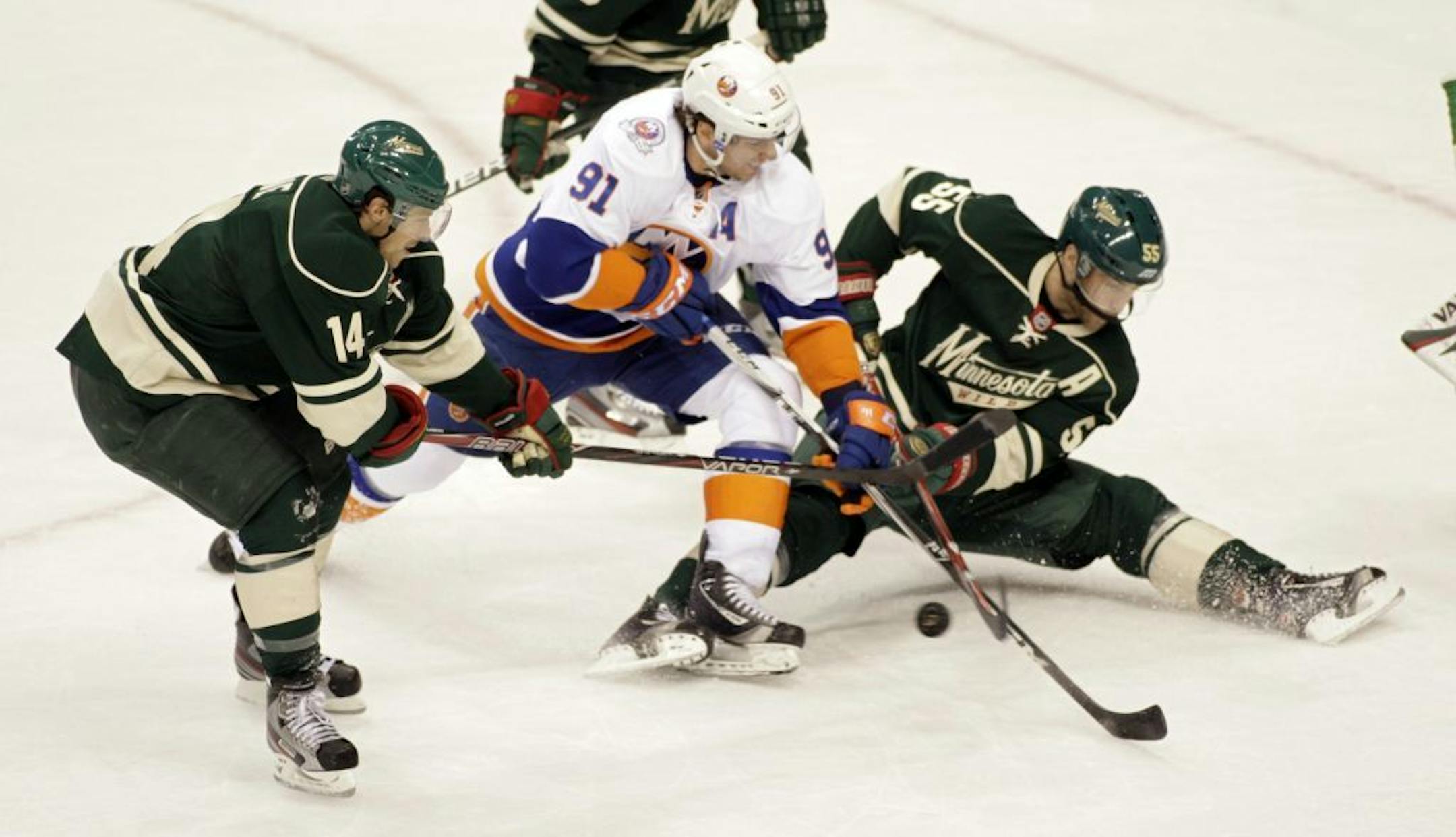 New York Islanders center John Tavares (91) battles for the puck with Minnesota Wild left wing Darroll Powe (14) and defenseman Nick Schultz (55) during the first period in an NHL hockey game, Saturday, Dec. 17, 2011, in St. Paul, Minn.