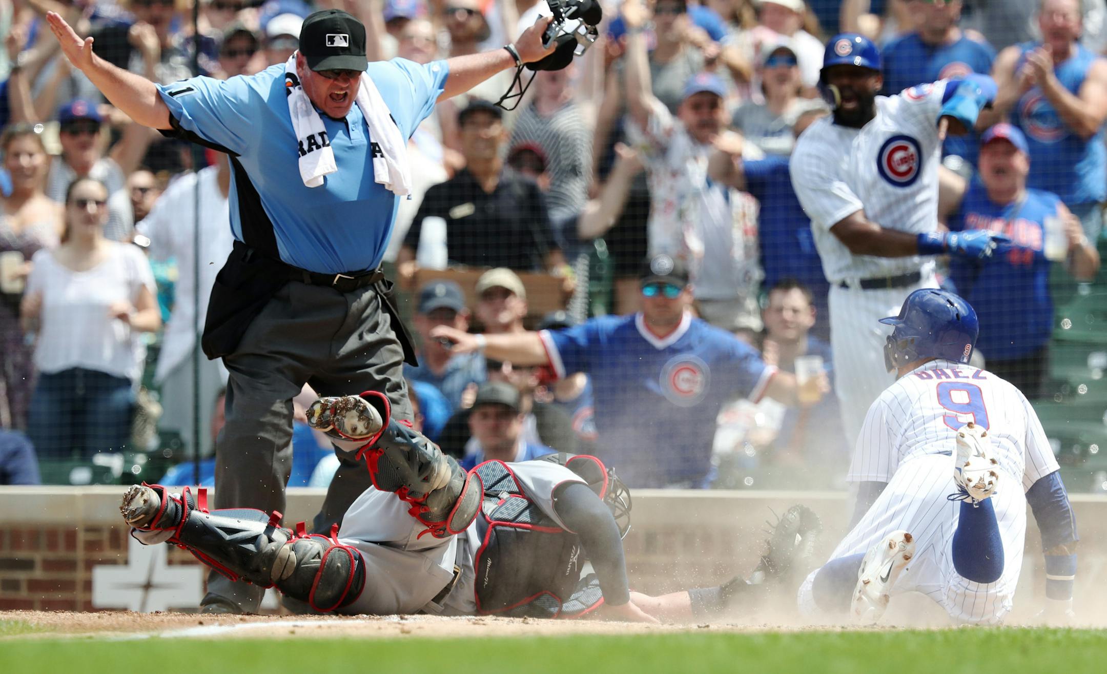 Home plate umpire Hunter Wendelstedt calls the Chicago Cubs' Javier Baez (9) safe at home plate as Minnesota Twins catcher Bobby Wilson reaches for Baez in the third inning at Wrigley Field in Chicago on Saturday, June 30, 2018. (John J. Kim/Chicago Tribune/TNS)