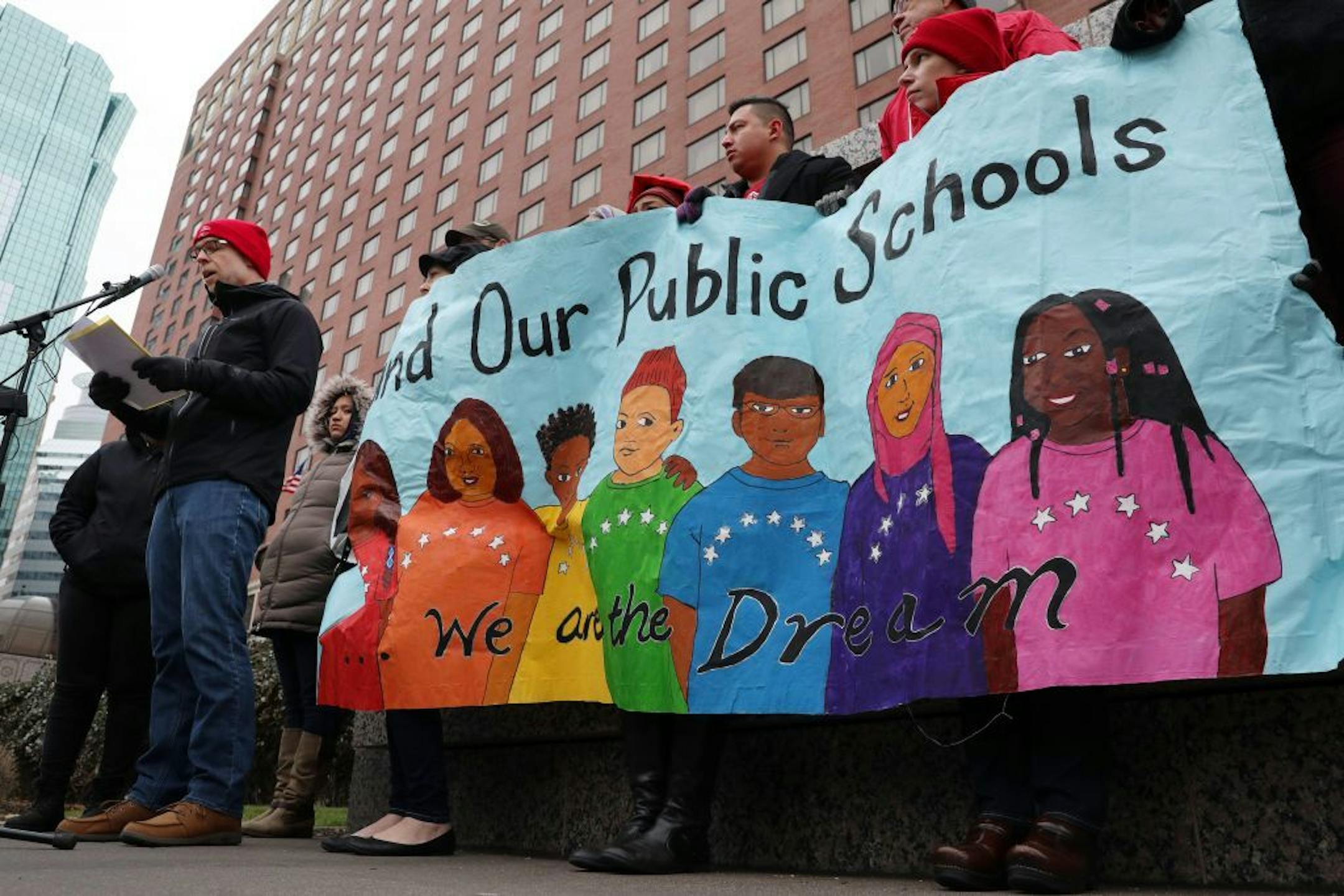 Nick Faber, president of the St. Paul Federation of Teachers, spoke as others held signs while they protested at a CEO luncheon outside the Hilton hotel.