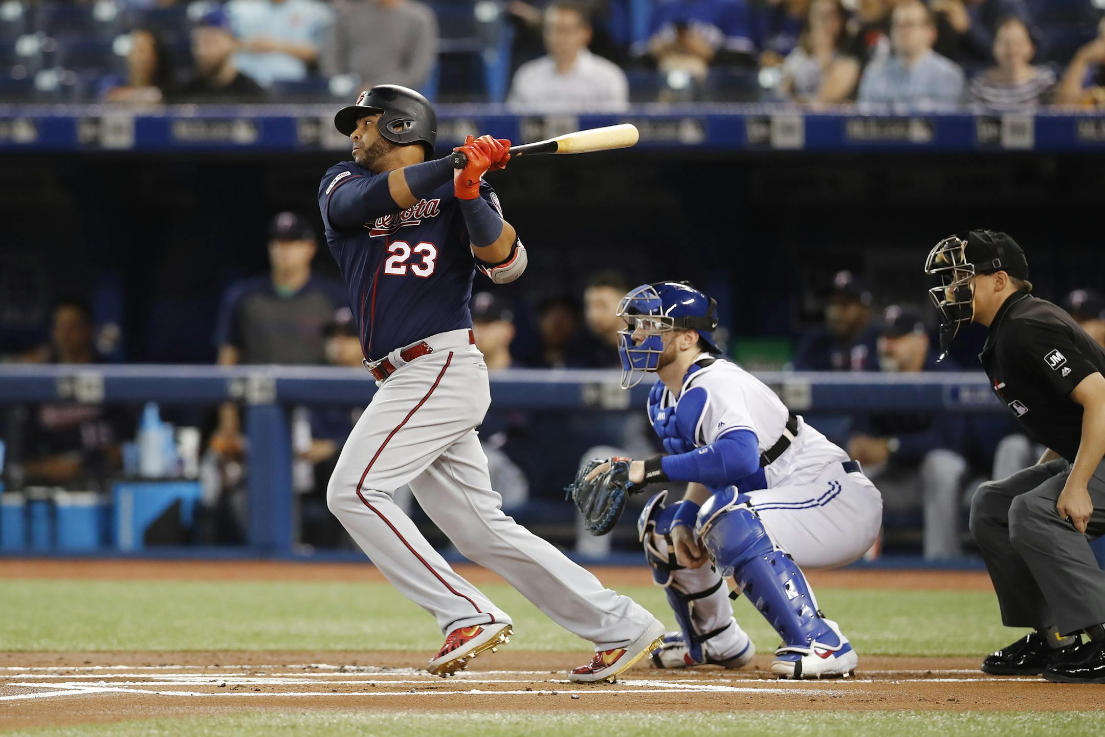 Minnesota Twins designated hitter Nelson Cruz (23) hits a single ahead of Toronto Blue Jays catcher Danny Jansen, second from right, during the first inning of baseball game action in Toronto, Monday, May 6, 2019. (Mark Blinch/The Canadian Press via AP)