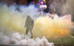 A demonstrator walked amid the tear gas emitted from canisters outside the Brooklyn Center Police Department Sunday night. ] JEFF WHEELER • jeff.whe