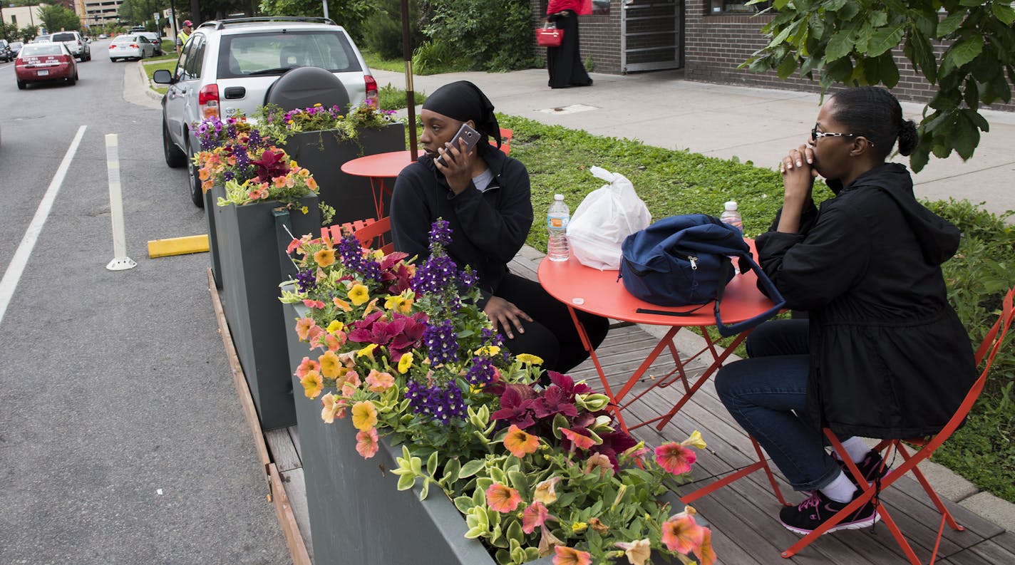 Shanay Ponder, left, answers a call while she sits with her mother, Inez Howard, at the new parklet seating outside of Twin Cities Coffee and Deli on Chicago Ave. on Wednesday. "This is the first time I've seen it," said Ponder of the new seating. "I love it." ] Isaac Hale &#xef; isaac.hale@startribune.com The city is expanding its Parklet program to include "street cafes", pop-up spaces to eat in curbside parking spots outside restaurants.