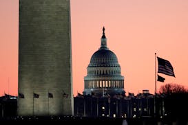 The U.S. Capitol building, center, is seen next to the bottom part of the Washington Monument, left, before sunrise on Capitol Hill in Washington, Thu