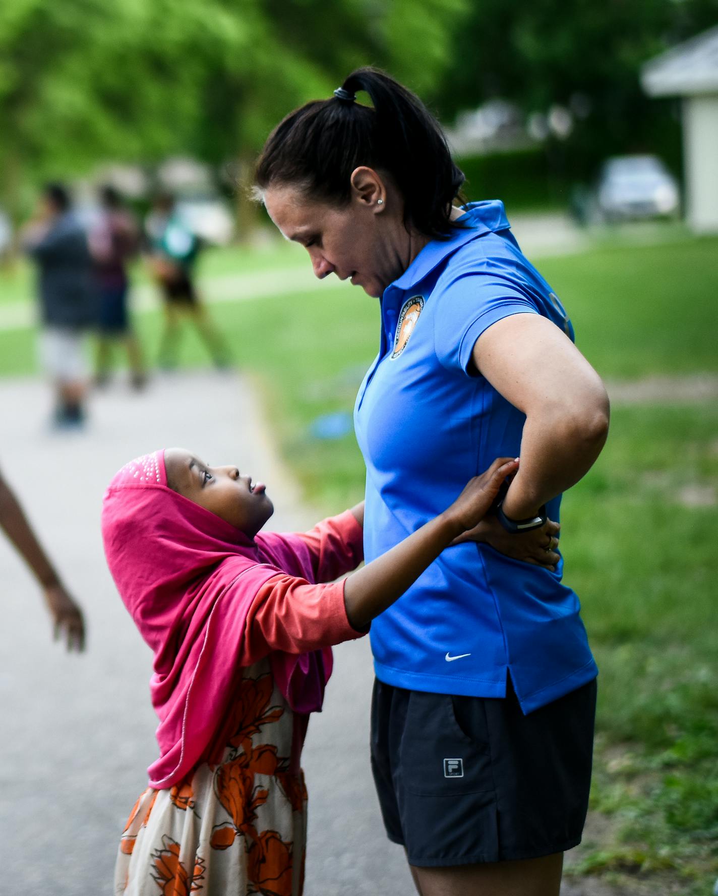 St. Cloud police officer Kelly Holden shared a moment with Zahur Abdi, 4, as a few dozen neighborhood kids played basketball behind them as part of Southside Hoops Tuesday night.