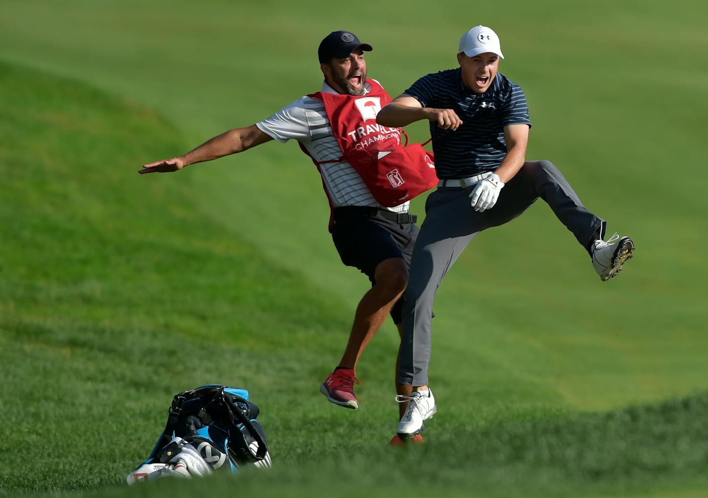 Jordan Spieth, right, celebrated with caddie Michael Greller after Spieth holed a bunker shot on a playoff hole to win the Travelers Championship golf tournament Sunday.