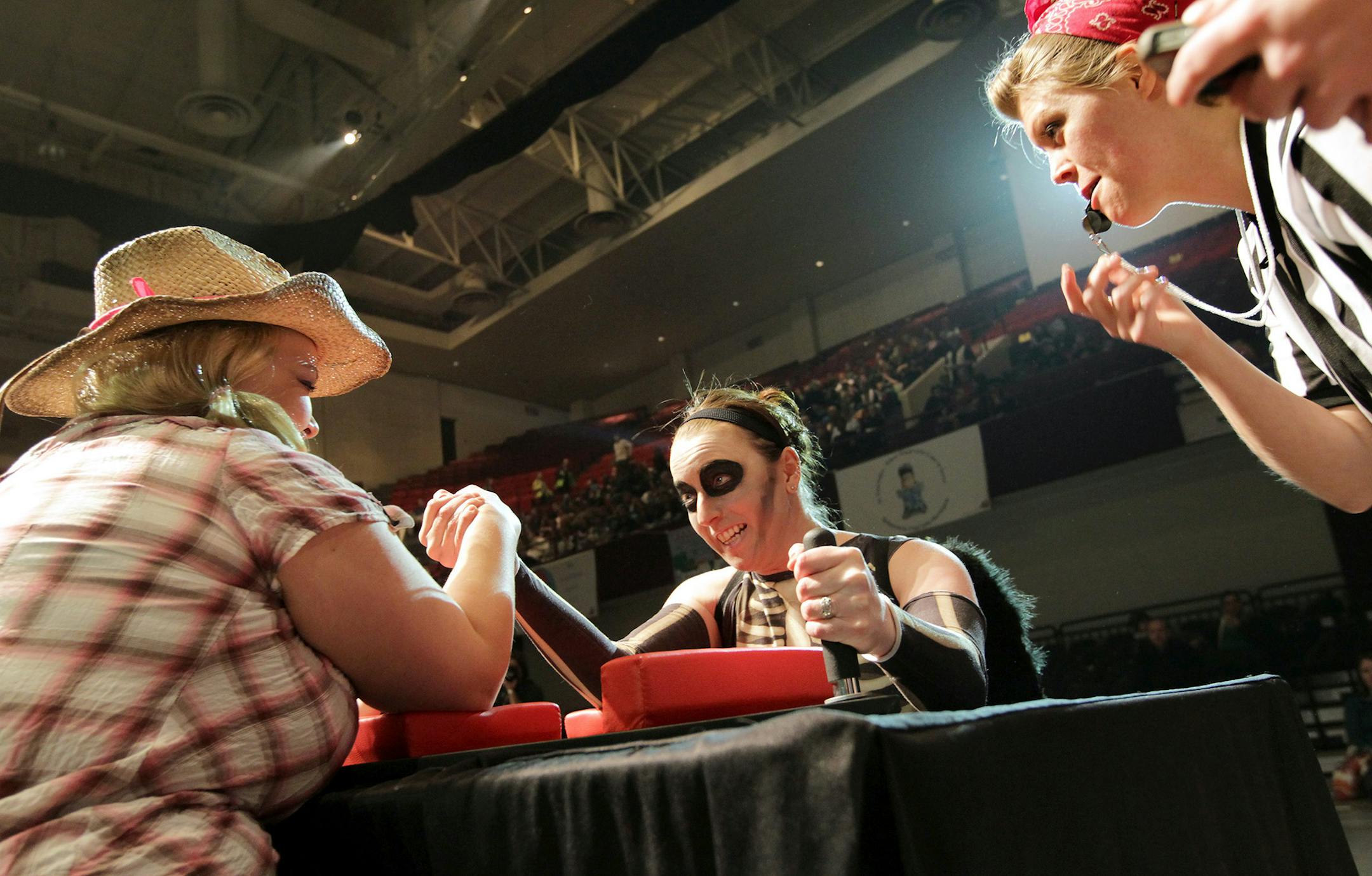 Angela "Death" Hershberger, center, faces Sara "Brawlly Parton" Larsen in a match referred by Hally "Hawkeye" Turner as the Minnesota Arm Wrestling League for Ladies holds a brief set of matches before the Minnesota Roller Girls tournament at Roy Wilkins Auditorium in St. Paul March 2, 2013. (Courtney Perry/Special to the Star Tribune)