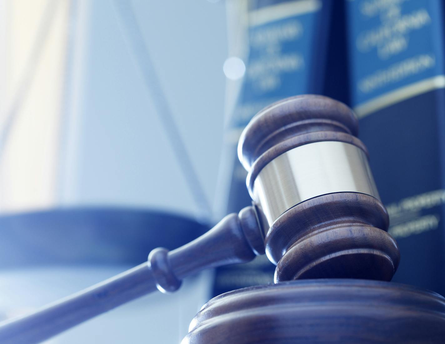 iStock A gavel rests on its sounding block with a several law books and a justice scale out of focus in the background.