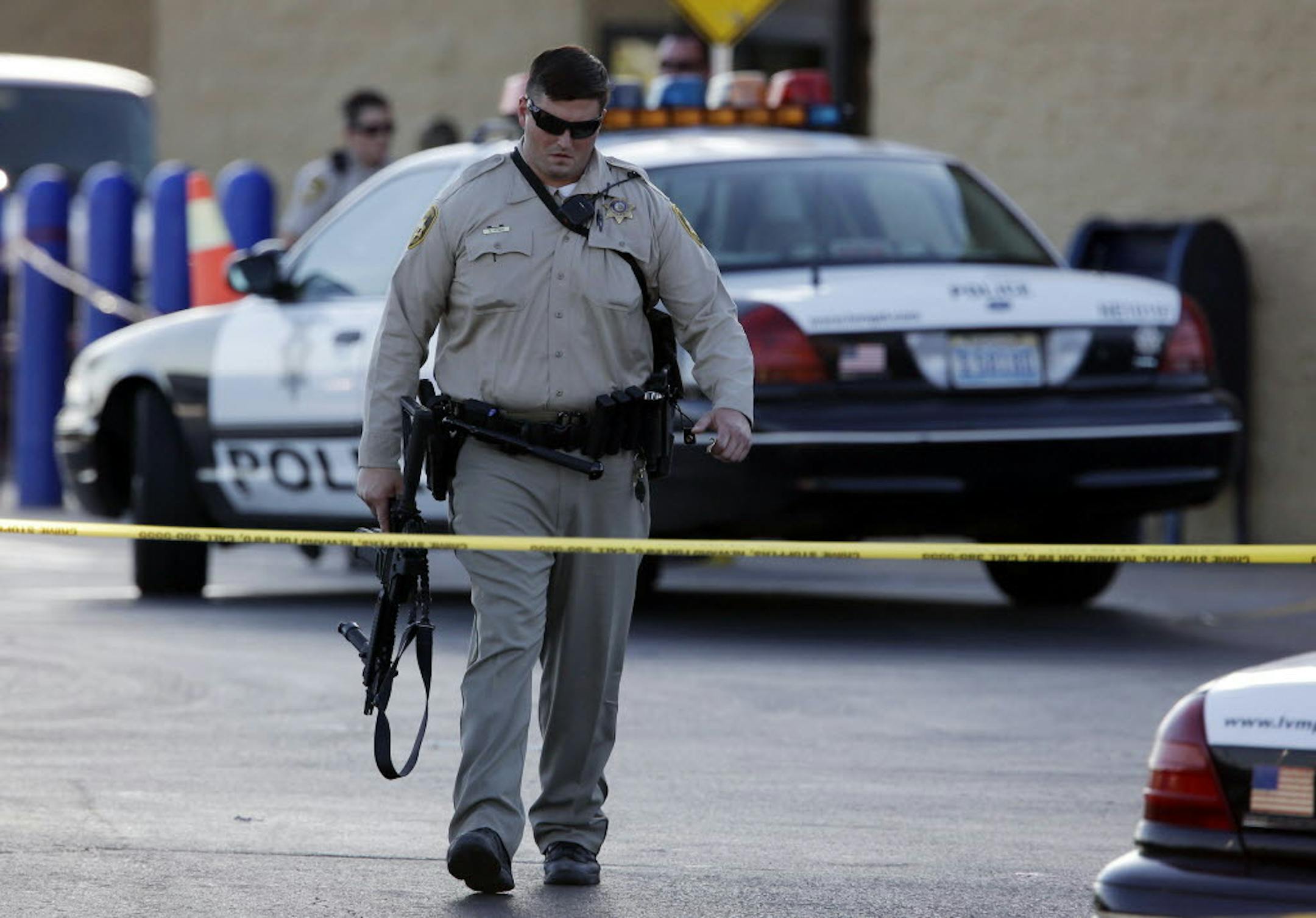 June 8, 2014: A Las Vegas police officer walks away from the scene of a shooting near a Wal-Mart. A man and a woman ambushed two police officers eating lunch at a Las Vegas restaurant, fatally shooting them at point-blank range before fleeing to a nearby Wal-Mart where they killed a third person and then themselves in an apparent suicide pact