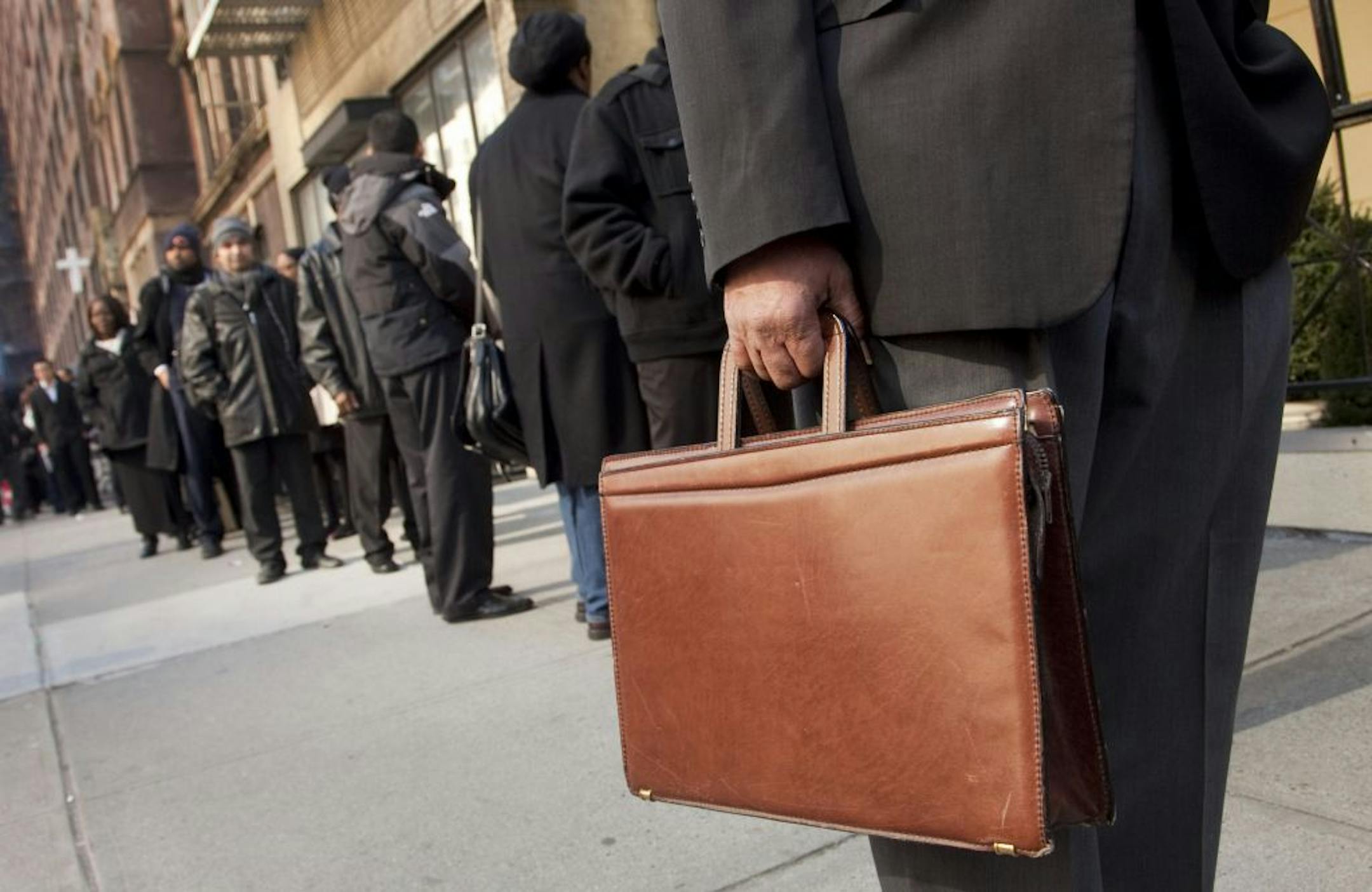 Dozens of job seekers line up to enter a National Career Fair in New York.