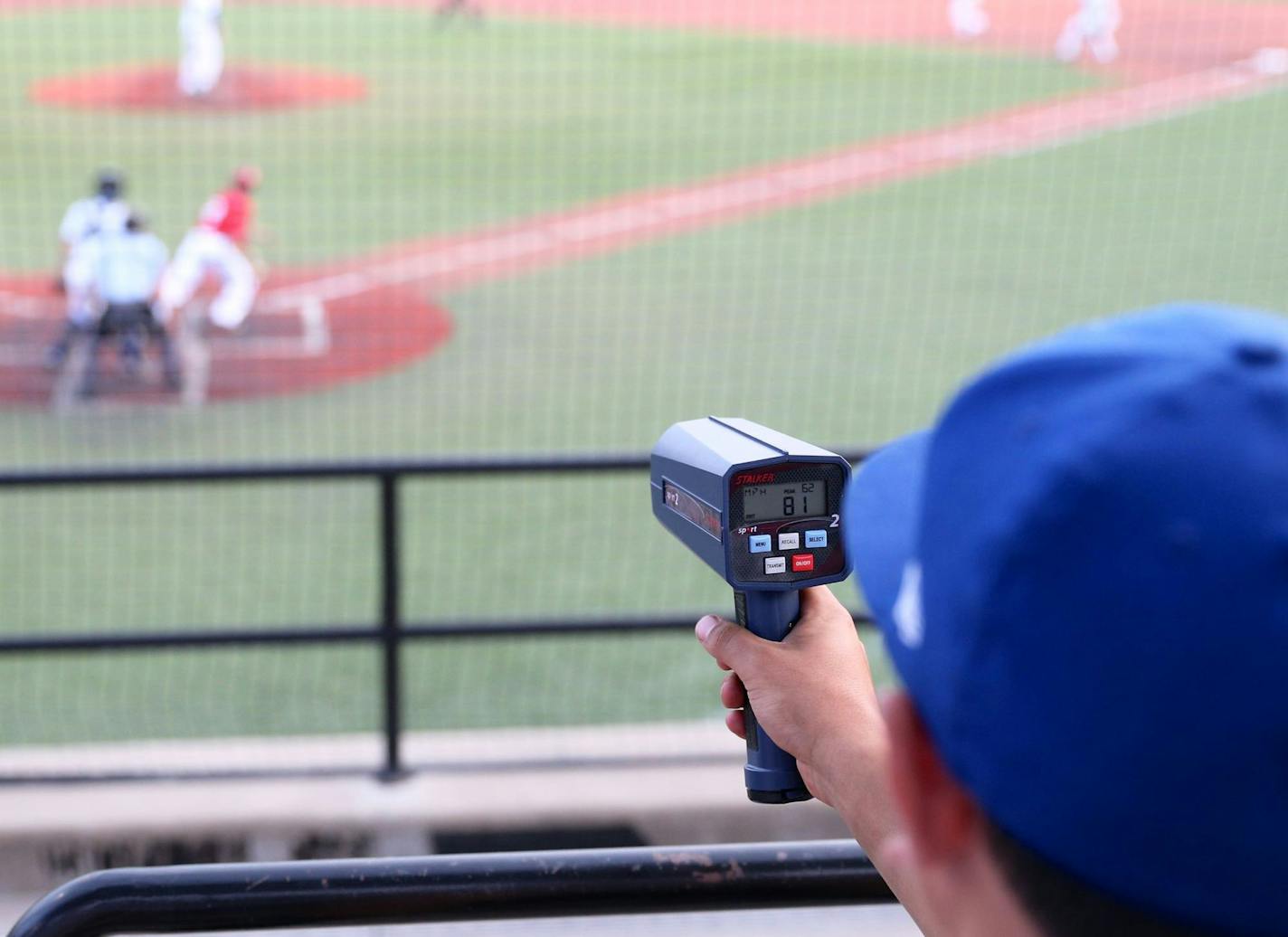 A Minnetonka player checks the radar gun for the speed of a pitch from a Skippers hurler.