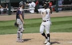 Chicago White Sox's Eloy Jimenez, right, celebrates after hitting a solo home run as Minnesota Twins catcher Mitch Garver looks to the field during th