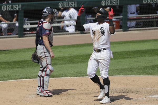 Chicago White Sox's Eloy Jimenez, right, celebrates after hitting a solo home run as Minnesota Twins catcher Mitch Garver looks to the field during th