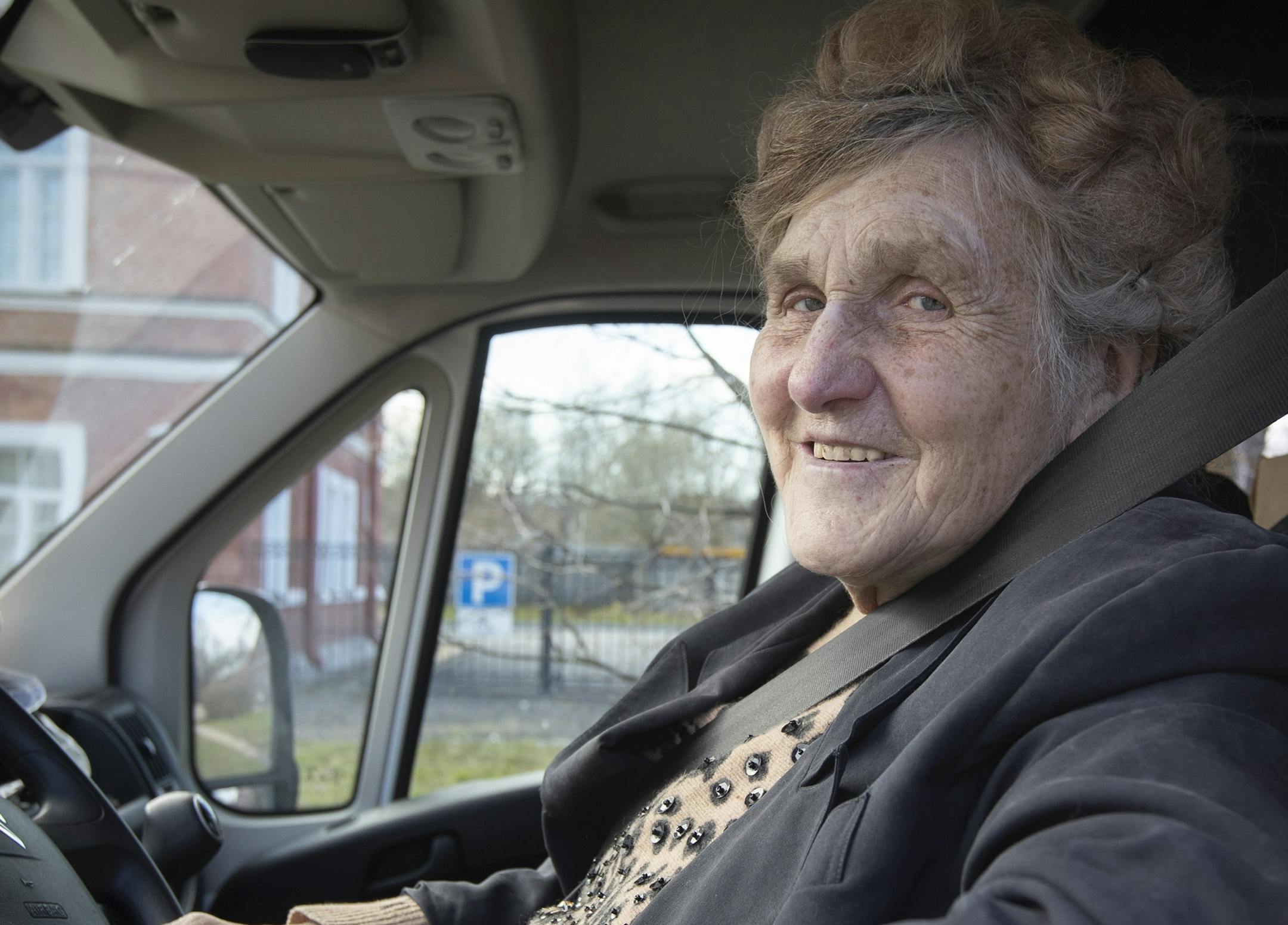 In this photo taken on Thursday, April 30, 2020, Galina Yakovleva sits in her van in St.Petersburg, Russia. Every day amid the coronavirus pandemic, 80-year-old Leningrad siege survivor Galina Yakovleva has driven to the city in her white minivan to bring charity groceries and goods to elderly people and families with children in need. (AP Photo/Dmitri Lovetsky)
