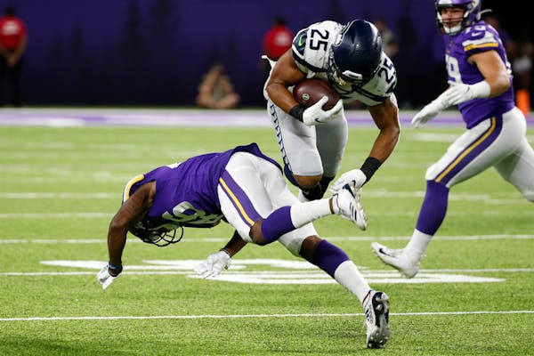Seattle running back Travis Homer (25) is upended by Vikings defender Bene Benwikere, left, during the second half of Sunday's game.