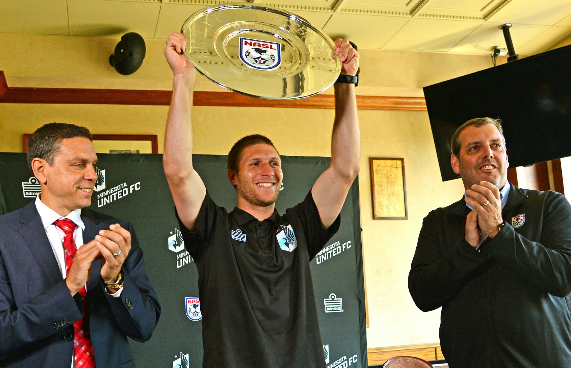 NASL Commissioner Bill Peterson, on the right Presented Minnesota United team member Justin Davis, With the 2014 Spring Season Trophy with Manny Lagos, Minnesota United head coach on the left. ].Minnesota United FC, celebrated at Brits Pub on Tuesday june10, 2014 for winning the Spring Season trophy. Richard.Sennott@startribune.com Richard Sennott/Star Tribune Minneapolis Minn. Tuesday 6/10/2014) ** (cq)