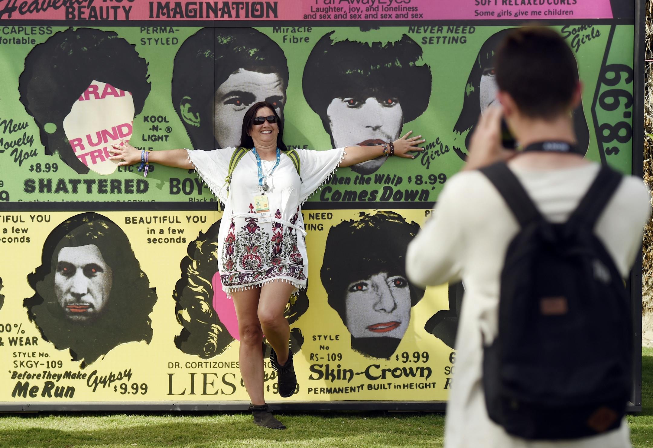 Kerry Kirschman of Littleton, Colo.,, is photographed by her son Ethan, 17, in front of a billboard of the cover of the Rolling Stones' 1978 album "Some Girls" on day 1 of the 2016 Desert Trip music festival at Empire Polo Field on Friday, Oct. 7, 2016, in Indio, Calif.