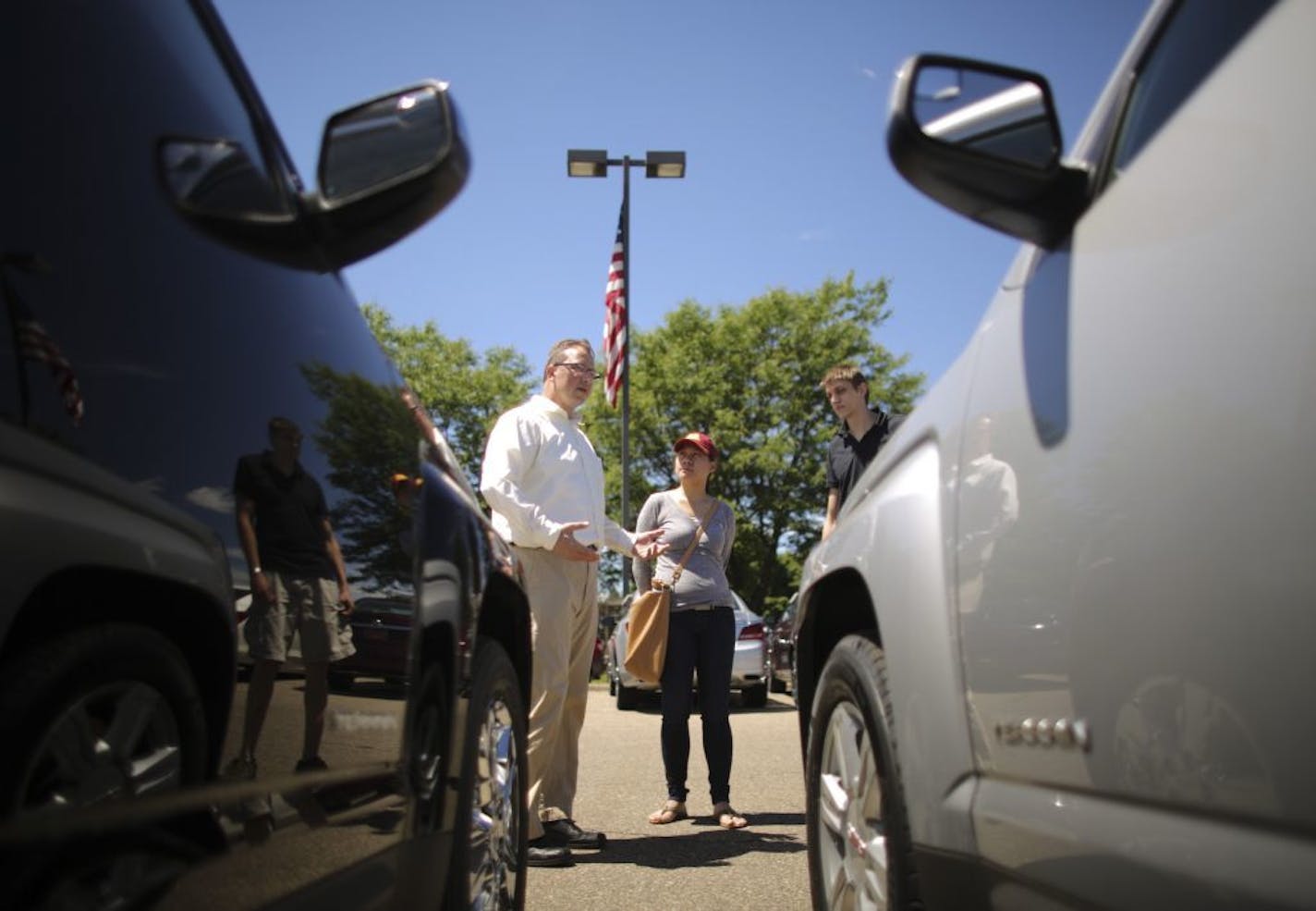 Mike Kienast, left, a salesman at the White Bear Lake Superstore, talked about the virtues of the GMC Terrain that Kia Lee, center, was about to test drive. She was there with Andrew Sellner at the dealership in White Bear Lake Wednesday afternoon.