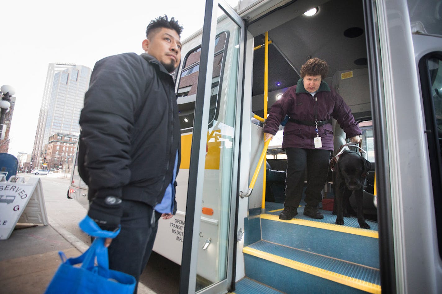 Lolly Lijewski, who uses a seeing eye dog named Jiffy for vision impairment, is helped off the Metro Mobility bus by driver Rigoberto Zuniga.