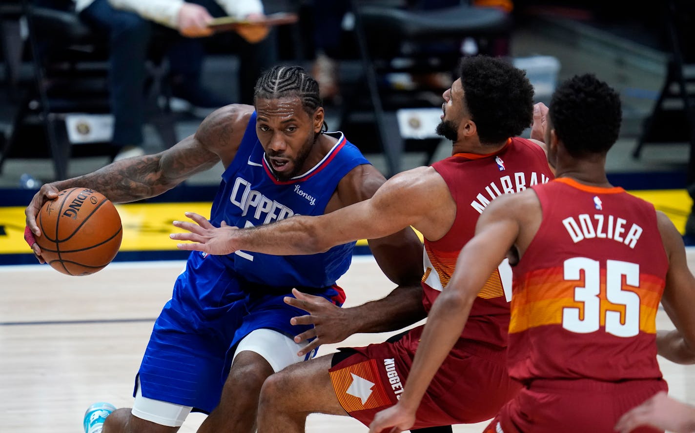 Los Angeles Clippers forward Kawhi Leonard, left, is defended by Denver Nuggets guards Jamal Murray, center, and PJ Dozier during the second half of an NBA basketball game Friday, Dec. 25, 2020, in Denver. (AP Photo/David Zalubowski)