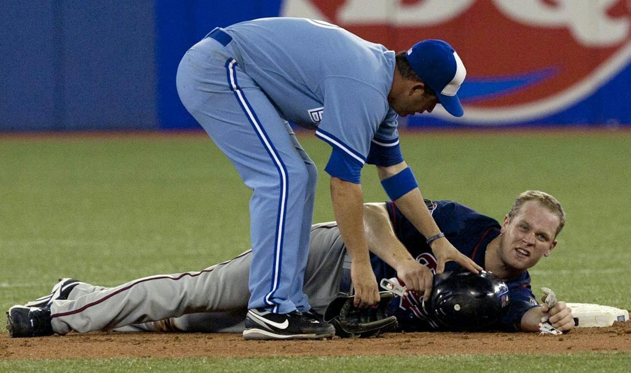 Toronto Blue Jays' John McDonald,left, checks on Minnesota Twins Justin Morneau, on July 7, 2010 -- the play that resulted in a concussion that ended Morneau's season and sharply changed the course of his career.