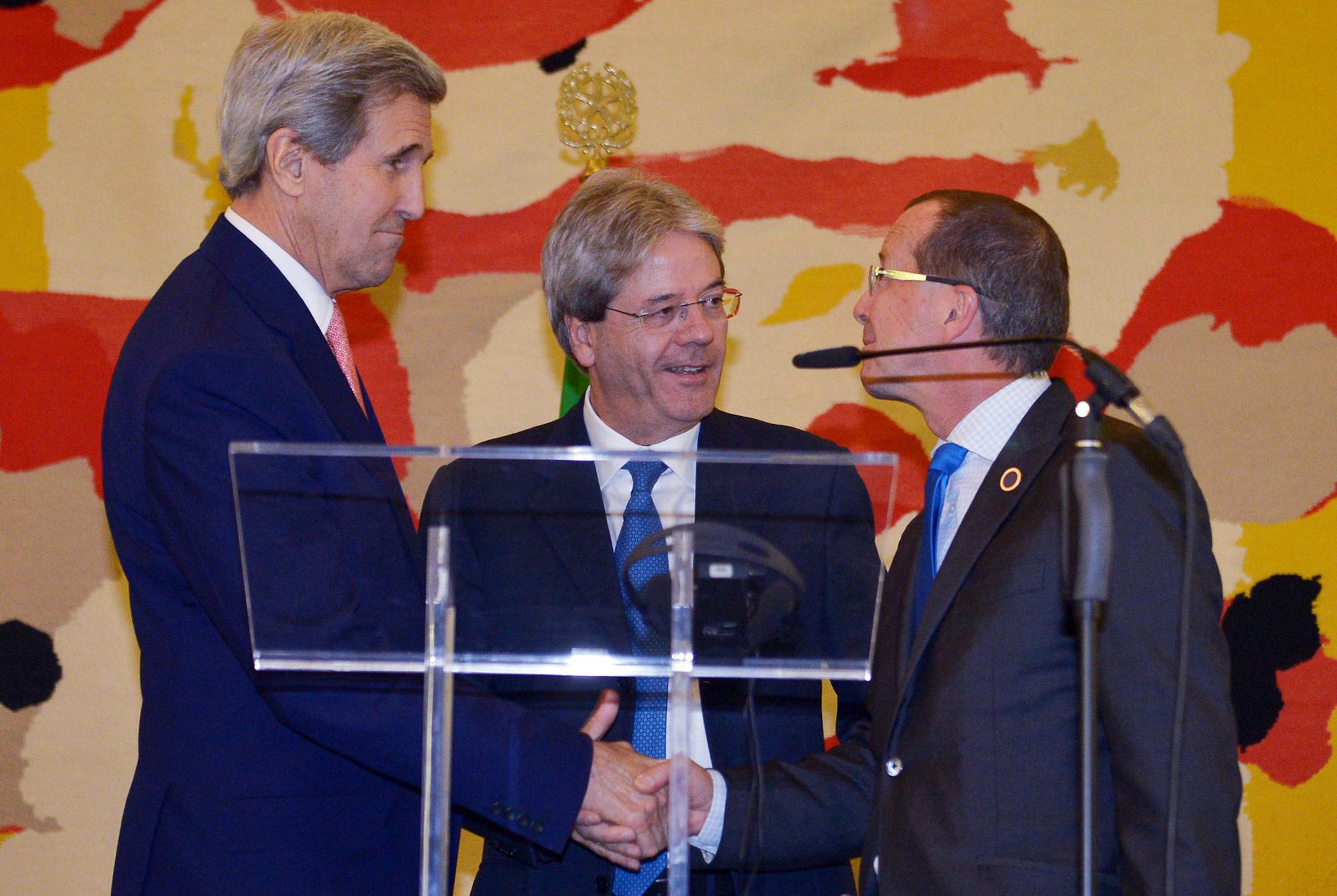 US Secretary of State John Kerry, left, Italian Foreign Minister Paolo Gentiloni, centre, and UN special envoy for Libya Martin Kobler shake hands after their press conference, following an international conference on Libya at the Ministry of Foreign Affairs in Rome, Sunday, Dec. 13, 2015. Foreign ministers were poised to endorse a U.N.-brokered national unity plan for Libya at a Rome conference aimed at prodding the North Africa country's bickering factions to fulfill their commitment to sign t