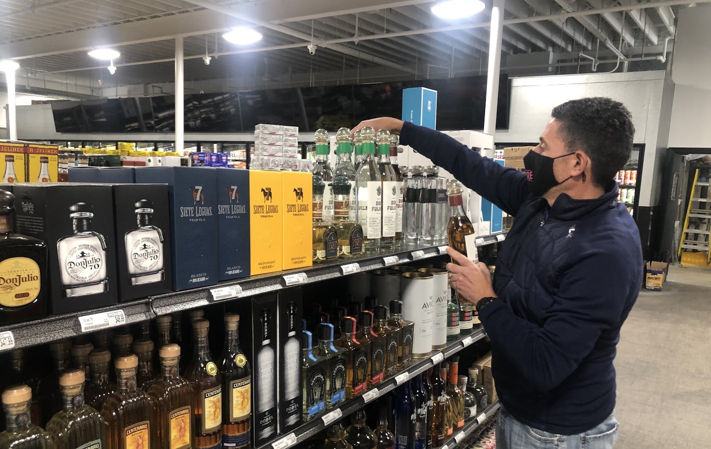 Chicago Lake Liquors owner John Wolf stocked shelves on Wednesday in preparation of the Thursday reopening after rioting and fires destroyed the interior in May after the death of George Floyd.