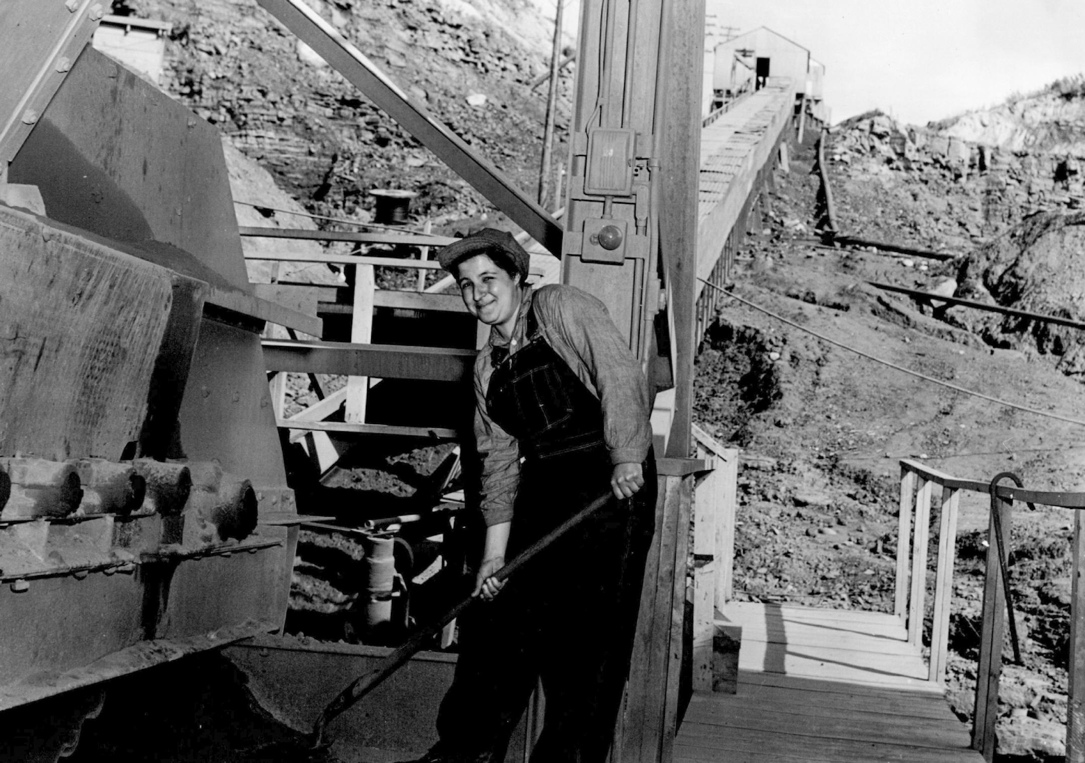 1943: Theresa Serratore with ore-spillage that has fallen from the conveyor belt feeder at the Butler Brothers mining company in Nashwauk-Keewatin.