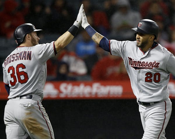 Minnesota Twins' Eddie Rosario, right, gets congratulations from Robbie Grossman after Rosario hits a solo home run against the Los Angeles Angels dur