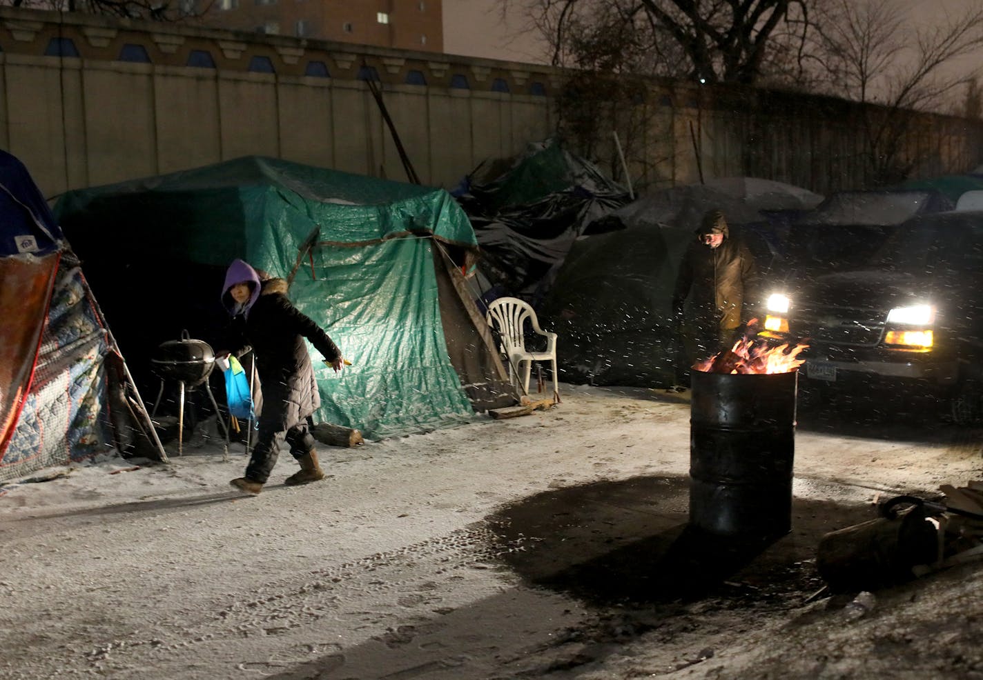 Inhabitants of a large homeless encampment in south Minneapolis prepare for an important deadline next week to relocate to a temporary shelter nearby. Here, headlights from a truck delivering firewood illuminate part of the Hiawatha homeless encampment as residents walk through Wednesday, November 28, 2018 in Minneapolis, MN. A Navigation Center with housing is being established at 2109 Cedar Ave., a 1.25-acre site adjacent to the Franklin Avenue METRO Blue Line station and looks to be ready for