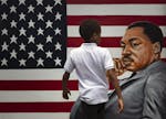 A young boy walks past a painting depicting Dr. Martin Luther King Jr. during a Juneteenth celebration in Los Angeles. Friday, June 19, 2020. Juneteen