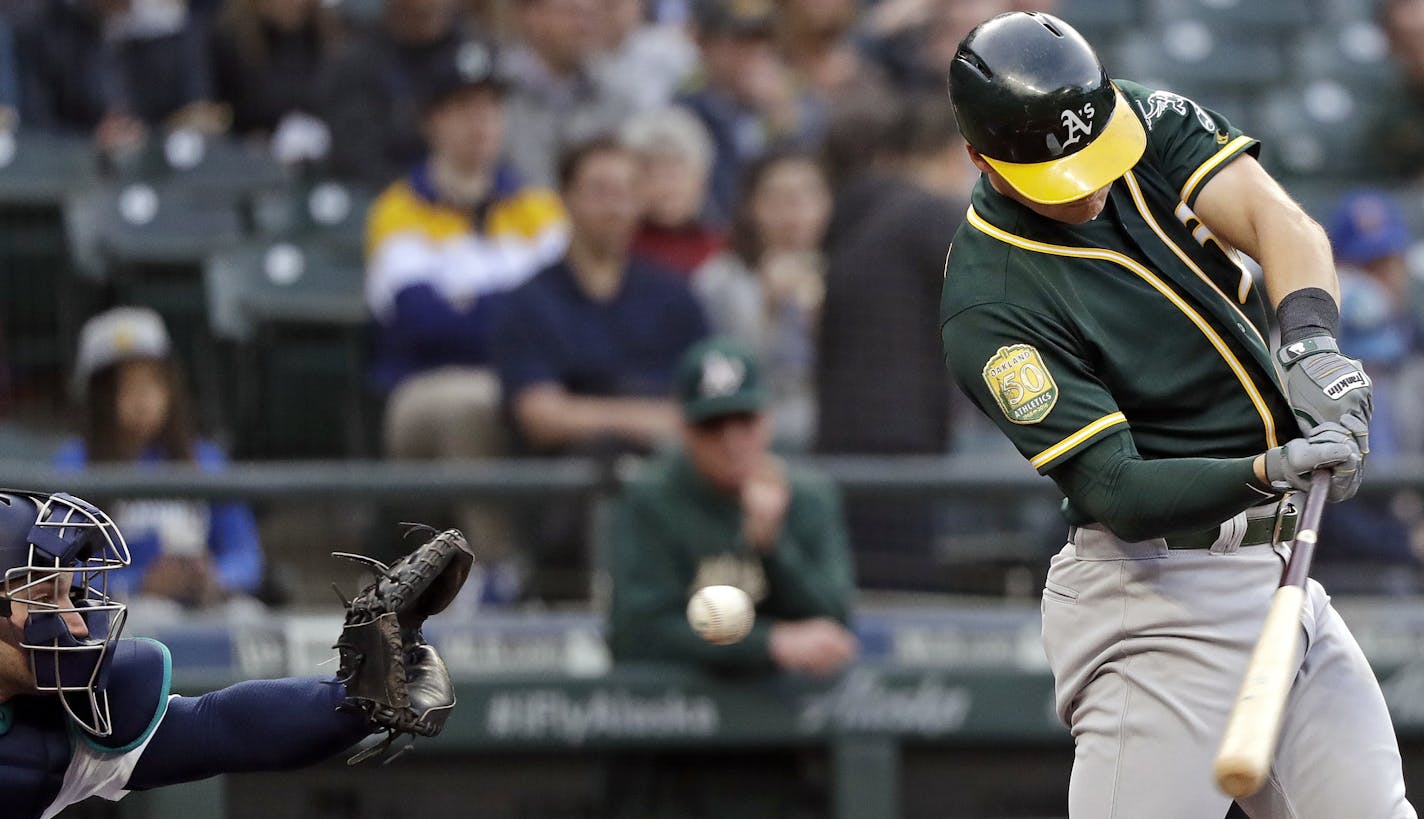 Oakland Athletics' Chad Pinder swings and misses to strike out as Seattle Mariners catcher Mike Zunino waits to catch the pitch during the first inning of a baseball game Wednesday, May 2, 2018, in Seattle. (AP Photo/Elaine Thompson)