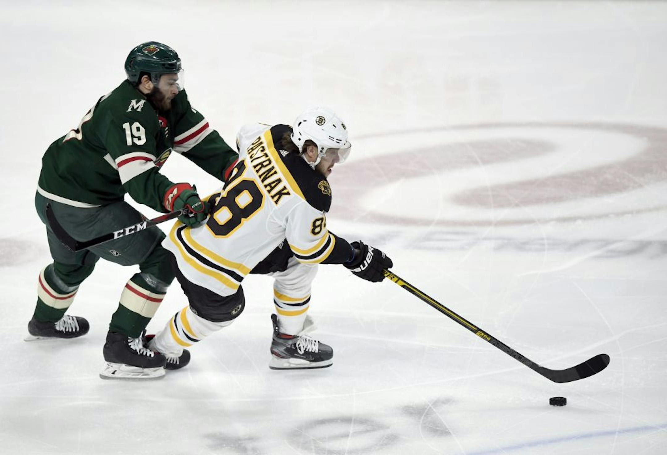 Boston Bruins' David Pastrnak (88), of the Czech Republic, has the puck against Minnesota Wild's Luke Kunin (19) during the first period of an NHL hockey game Saturday, Feb. 1, 2020, in St. Paul, Minn.